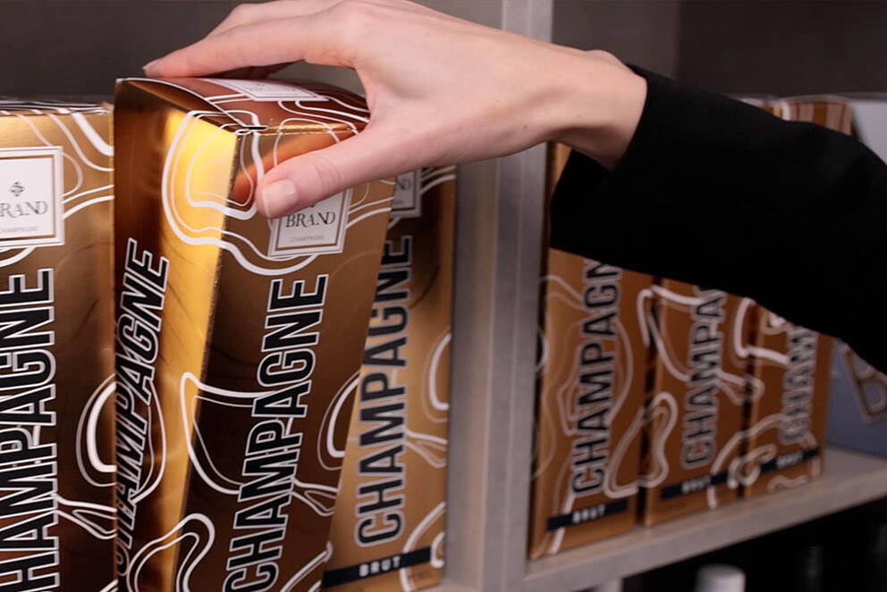 [Translate to Française:] Champagne packaging with cold foil, being taken from a shelf